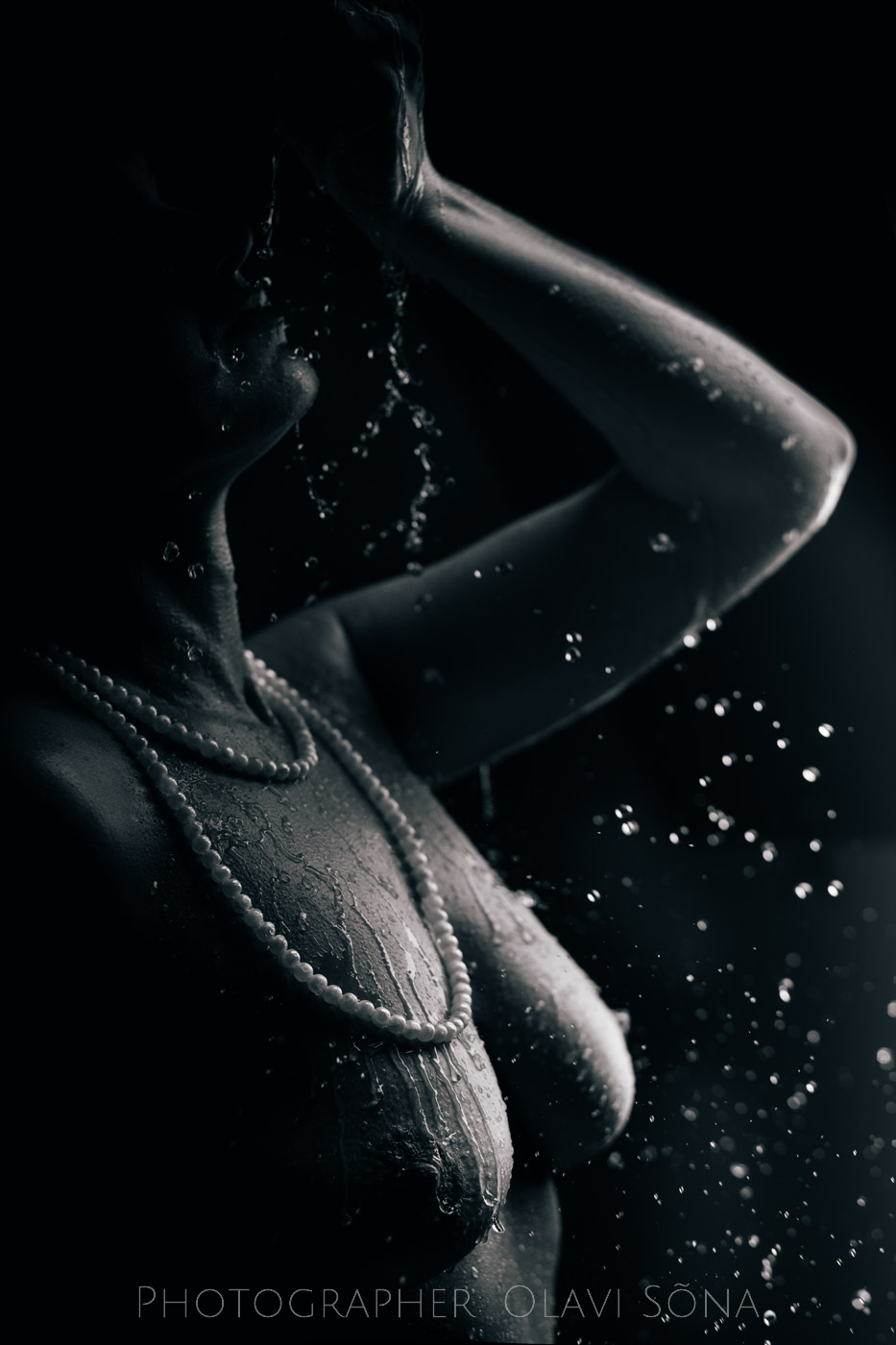 Woman pouring water on her self. She is nude and wearing pearls